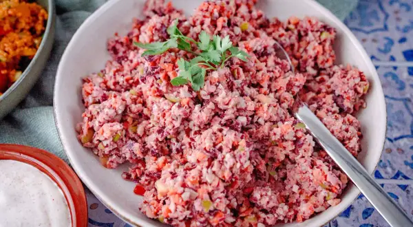 Bunter Karottensalat, frisch zubereitet im Thermomix, garniert mit Petersilie. Daneben eine Schale mit cremiger Sauce.