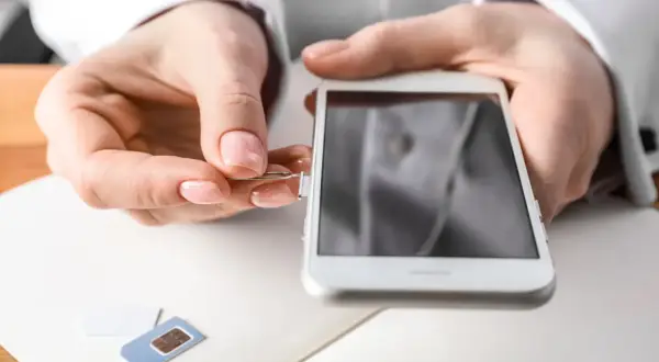 Maintenant, découvrez comment ouvrir le tiroir carte sim sans outil. Une main insère un trombone dans le téléphone.