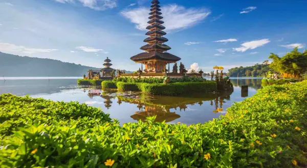 Świątynia Pura Ulun Danu Bratan na Bali podczas pory suchej. Woda spokojna, odbija wielopoziomową wieżę.