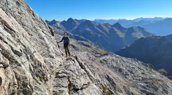 Wanderer auf dem Heilbronner Weg, gesichert an einem Stahlseil, genießt die atemberaubende Bergkulisse.
