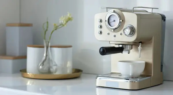 Kaffee-Ecke-Ideen: Eine elegante Espressomaschine mit Tasse und einer kleinen Vase mit Blumen.