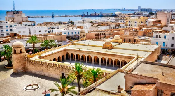 Widok z lotu ptaka na medynę Sousse z meczetem, palmami i morzem w tle.