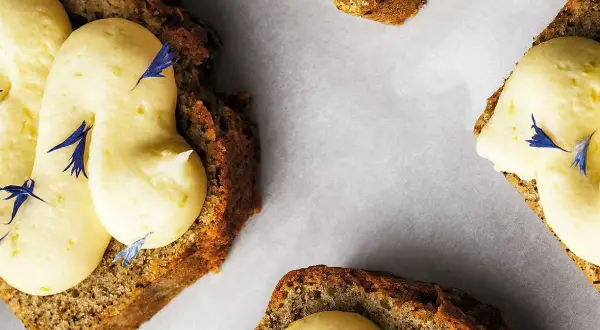 Skivor av saftig sockerkaka med fluffig frosting och blå blomblad. Perfekt att baka med bikarbonat för en luftig kaka.