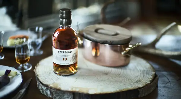 Bouteille d'Aberlour 18 ans, un whisky d'exception, posée sur une tranche de bois. Une expérience de dégustation unique, fruit d'une **création whisky** raffinée.