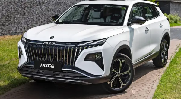 Biały, chinski suv premium z imponującym grillem i nowoczesnymi światłami, zaparkowany na podjeździe z kostki brukowej.