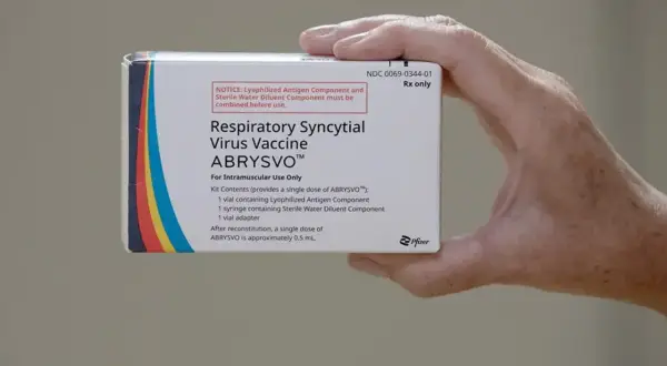 Dłoń trzyma pudełko szczepionki ABRYSVO™ przeciw wirusowi RSV.