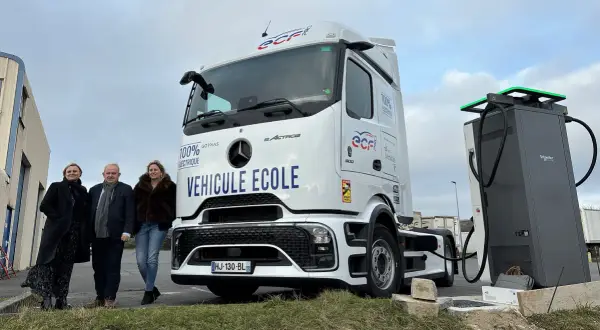 Trois personnes posent devant un camion école 100% électrique, prêt à être rechargé. L'avenir des camions électriques est en marche.