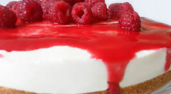 Cheesecake ai lamponi con coulis rosso e lamponi freschi, una delizia per gli occhi e per il palato.