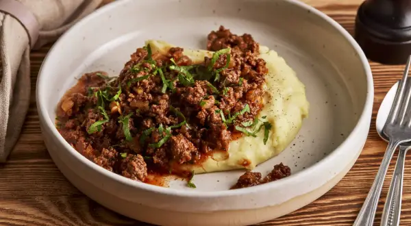 Herzhaftes Hackfleisch mit Tomatensauce auf cremigem Kartoffelpüree, garniert mit Petersilie. Ein einfaches und leckeres Haschee Rezept.