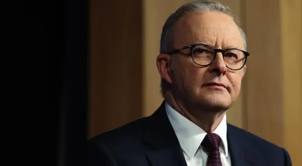 Primo piano di Anthony Albanese, uno dei più noti personaggi famosi australiani, con occhiali e abito scuro.