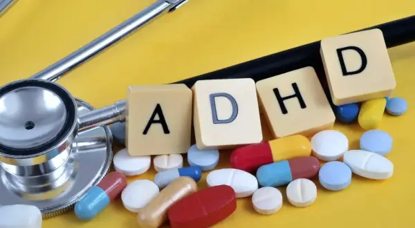 Stetoskop i tabletki symbolizujące leki na ADHD. Litery A, D, H, D ułożone obok.