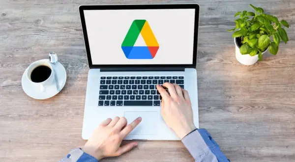 Frustrated hands try to access Google Drive on a laptop, but the screen shows only the logo, suggesting it's not loading.