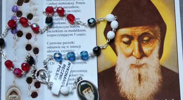 Koronka do św. Charbela, z kolorowymi paciorkami i medalikiem, obok wizerunku świętego. Idealna do odmawiania litanii do św. Charbela 9 dni.