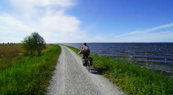 Rowerzysta przemierza malownicze trasy rowerowe Szczecin wzdłuż jeziora.