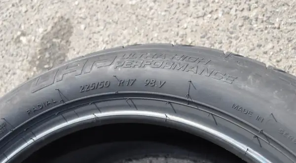 Opona samochodowa z napisem "ULTRA HIGH PERFORMANCE", rozmiar 225/50 R17 98V. Wygląda jak kormoran nurkujący w wodę.