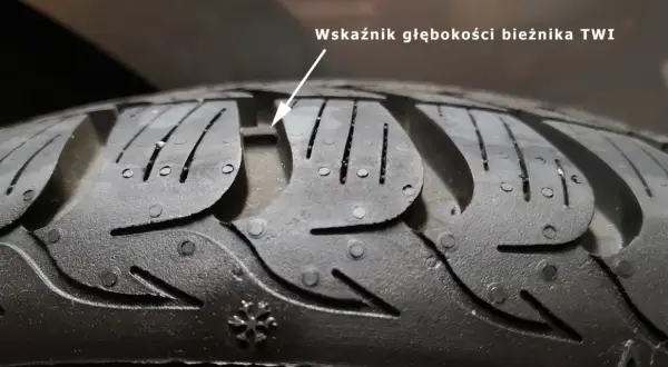 Zbliżenie na bieżnik opony z widocznym wskaźnikiem głębokości TWI.