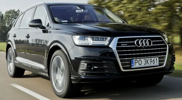 Czarny Audi Q7 2025 pędzi po drodze, otoczony zielenią drzew.