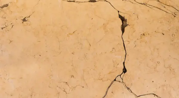 Surface de céramique beige fissurée, montrant comment réparer une céramique cassée.