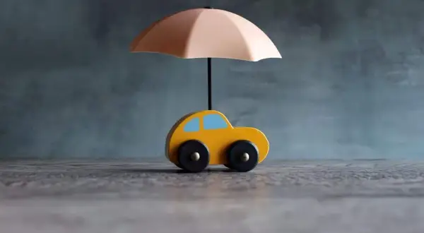 Voiture jaune sous parapluie, symbolisant une assurance courte durée.