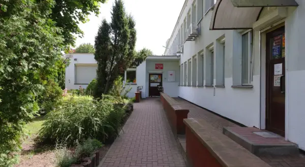 Wejście do Miejskiego Ośrodka Pomocy Rodzinie w Kielcach. Zadbany teren zielony i podjazd dla wózków.