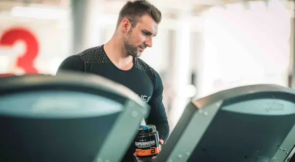 Mężczyzna z odżywką Supernova na bieżni, zastanawia się, czy robić cardio na masie.