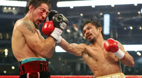 Intensiv boxning match där en boxare träffas hårt i ansiktet. Blod stänker och motståndaren levererar en kraftfull slag.