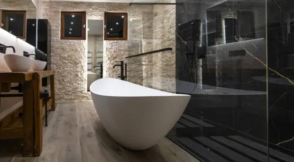 Salle de bain moderne avec baignoire îlot blanche et douche à l'italienne aux murs de marbre noir.