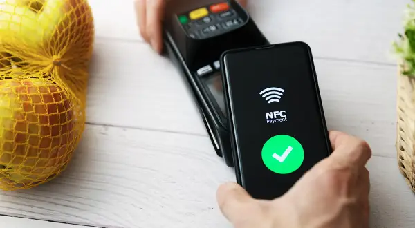 Płatność zbliżeniowa telefonem. Ekran pokazuje "NFC Payment" i zielony znaczek. Dowiedz się, jak włączyć NFC w telefonie, by płacić wygodnie.