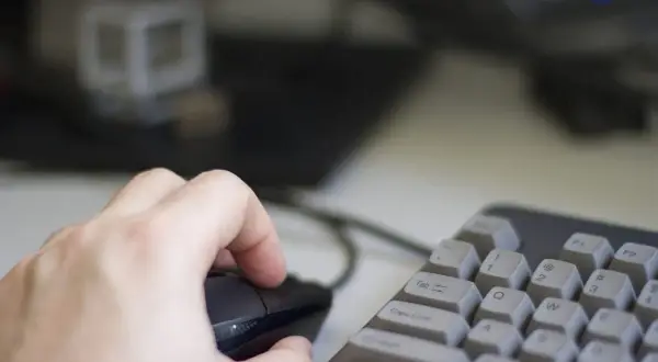 Dłoń trzyma myszkę, klawiatura w pobliżu. Używanie trybu incognito do prywatnego przeglądania.