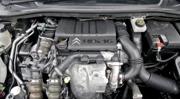 Silnik Citroen C4 1.6 HDI, widok z góry. Widać turbosprężarkę, przewody i osłonę silnika z logo producenta.