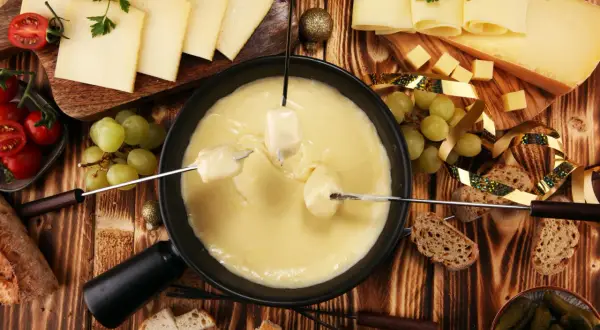 Fondue au fromage, une spécialité Auvergne Rhône Alpes, avec pain, raisins et tomates.