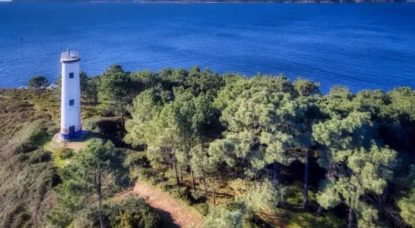 El faro de Cabo Home se alza solitario en una colina verde, vigilando el azul intenso del mar y las islas lejanas.