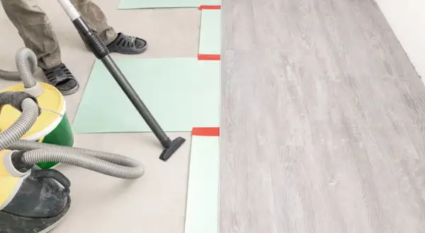 Préparation du sol avant la pose du parquet : nettoyage avec aspirateur. Le temps de séchage du ragréage est crucial.