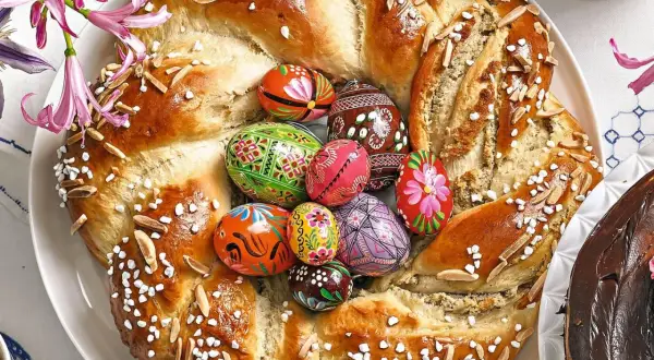 Ein festlicher Osterkranz aus Hefeteig, verziert mit bunten Ostereiern, Mandeln und Zuckerperlen.