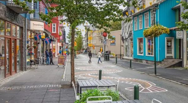 Kolorowa ulica w Reykjaviku, z flagami Islandii i szyldem "korona islandzka kantor".
