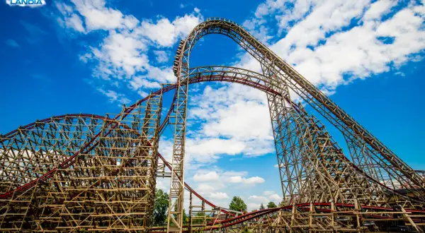 Drewniany rollercoaster w Energylandii, z czerwonymi torami i niebieskim niebem. To prawdziwa zadra przeciążenia, która wznosi się ku chmurom.