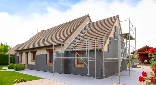 Maison en cours d'isolation par l'extérieur. Les inconvénients sont visibles : échafaudages, accès gêné, et aspect inachevé.