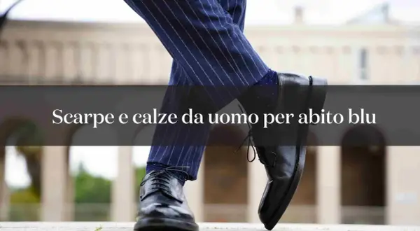 Primo piano di un uomo con abito blu gessato e calze blu a pois, abbinate a scarpe eleganti nere.