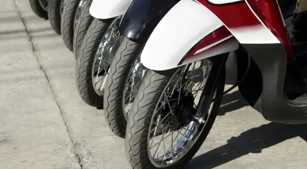 Rzędy motocykli gotowe do dpd transportu. Widoczne koła, opony i błotniki w kolorze białym, czarnym i czerwonym.
