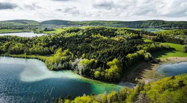Paysage jurassien avec lacs et forêts verdoyantes, idéal pour une randonnée Jura 5 jours.