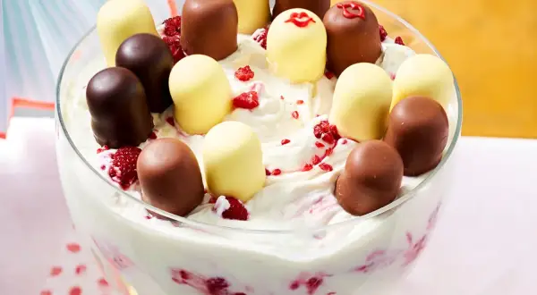 Schokoladen- und weiße Schaumküsse auf einer cremigen Nachspeise mit Himbeeren in einer Glasschüssel.