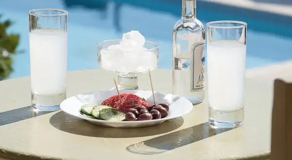 Ouzo, grecki alkohol, podawany z oliwkami i ogórkiem, przy basenie, jak na wakacjach pod Partenonem.