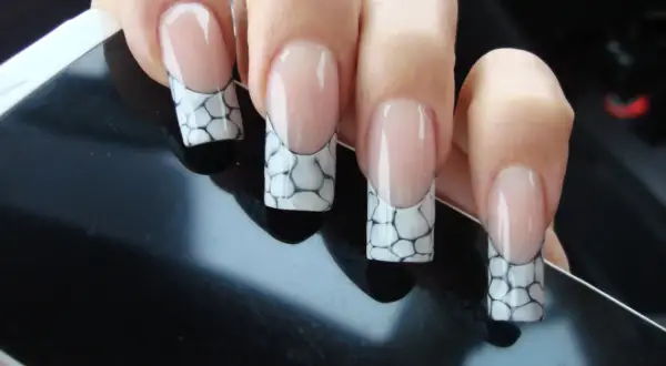 Manucure française avec un motif écaille de tortue sur les ongles, posée sur un écran noir.