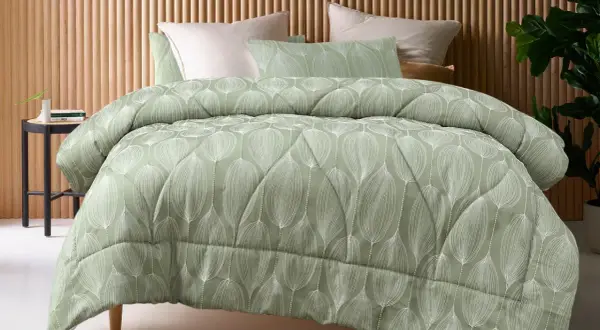 A sage green coverlet with a white leaf pattern. This coverlet serves as a decorative top layer for the bed, adding warmth and style.