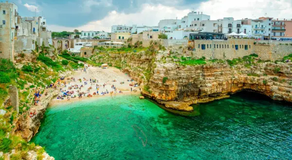 Malownicza plaża Polignano a Mare z turkusową wodą, skalistymi klifami i białymi budynkami na szczycie.