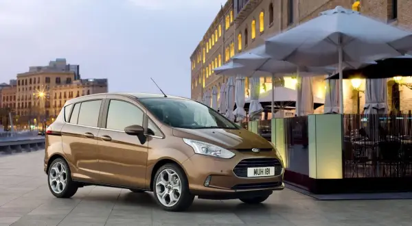 Brązowy Ford B-Max na tle miejskiej zabudowy. Idealny do miasta, jego wymiary sprawiają, że parkowanie to przyjemność.