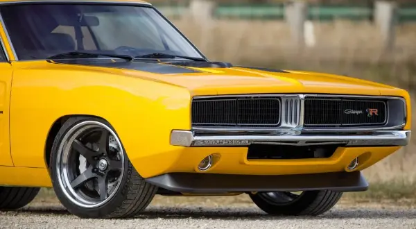 Żółty Dodge Charger 1970 z czarnymi pasami na masce i chromowanym grillem.
