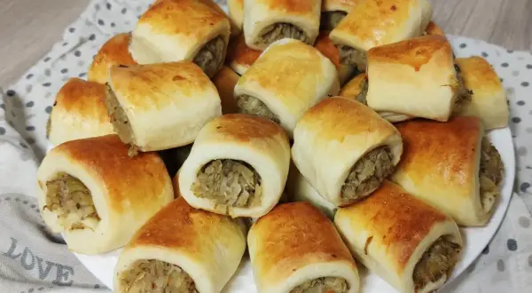 Złociste paszteciki z pieczarkami i kapustą, ułożone na talerzu, kuszą swoim wyglądem i aromatem.