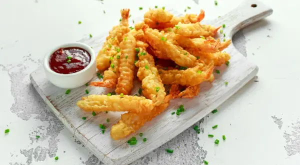 Chrupiące krewetki w tempurze do sushi, podane z sosem. Idealne na przekąskę lub jako dodatek do dań.