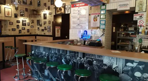 Stylowy bar z zielonymi stołkami i czarno-białą fototapetą. Idealne miejsce, gdzie na drinka w Krakowie.